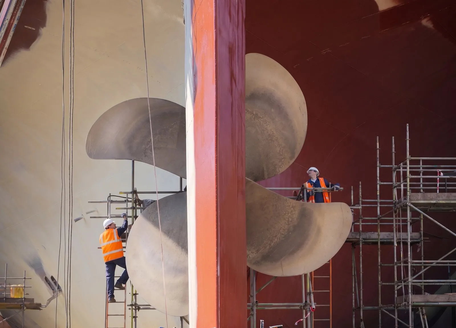 Technicians inspecting a vessel's propellers in dry dock.